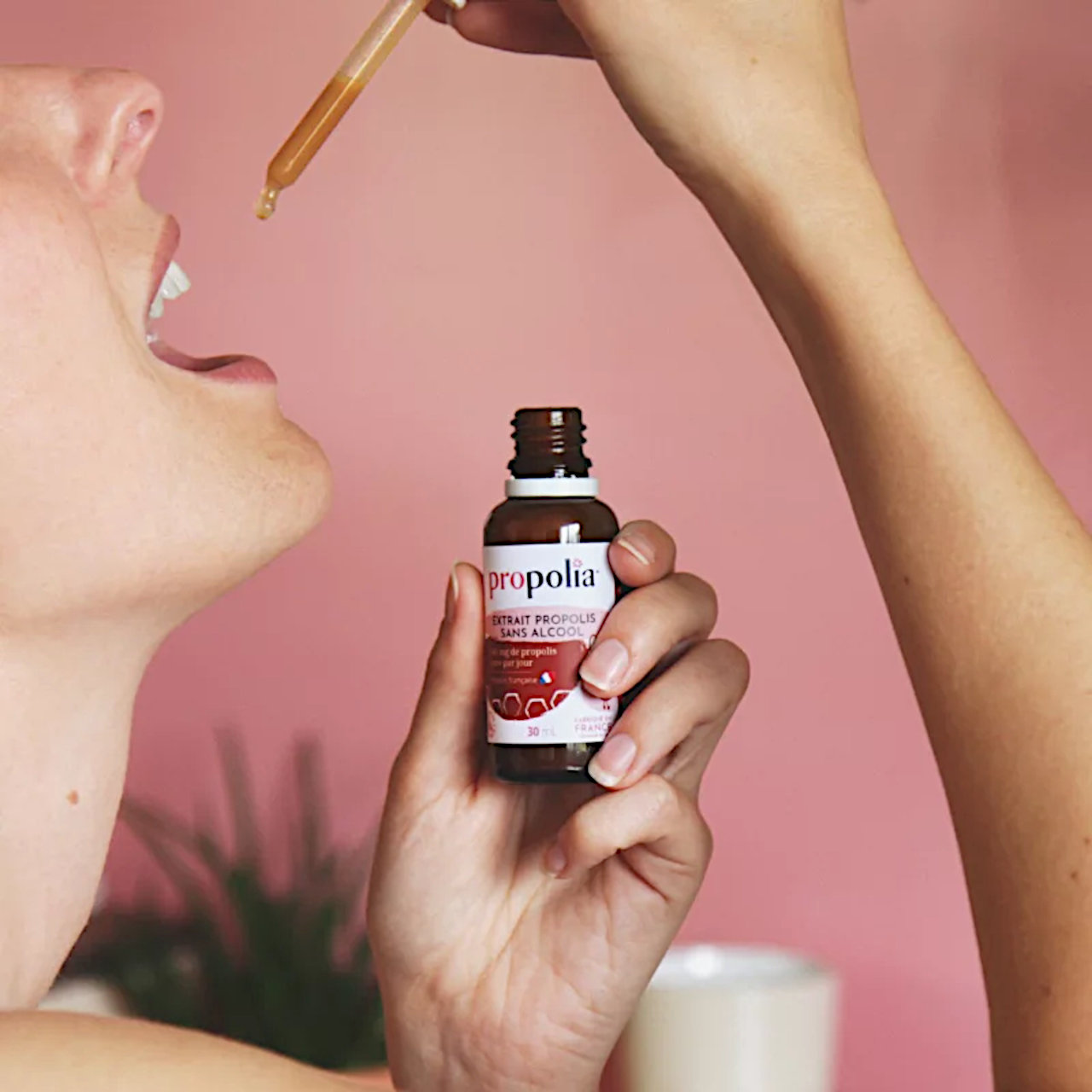 Weibliche Person träufelt sich Propolisextrakt mit Pipette in Mund